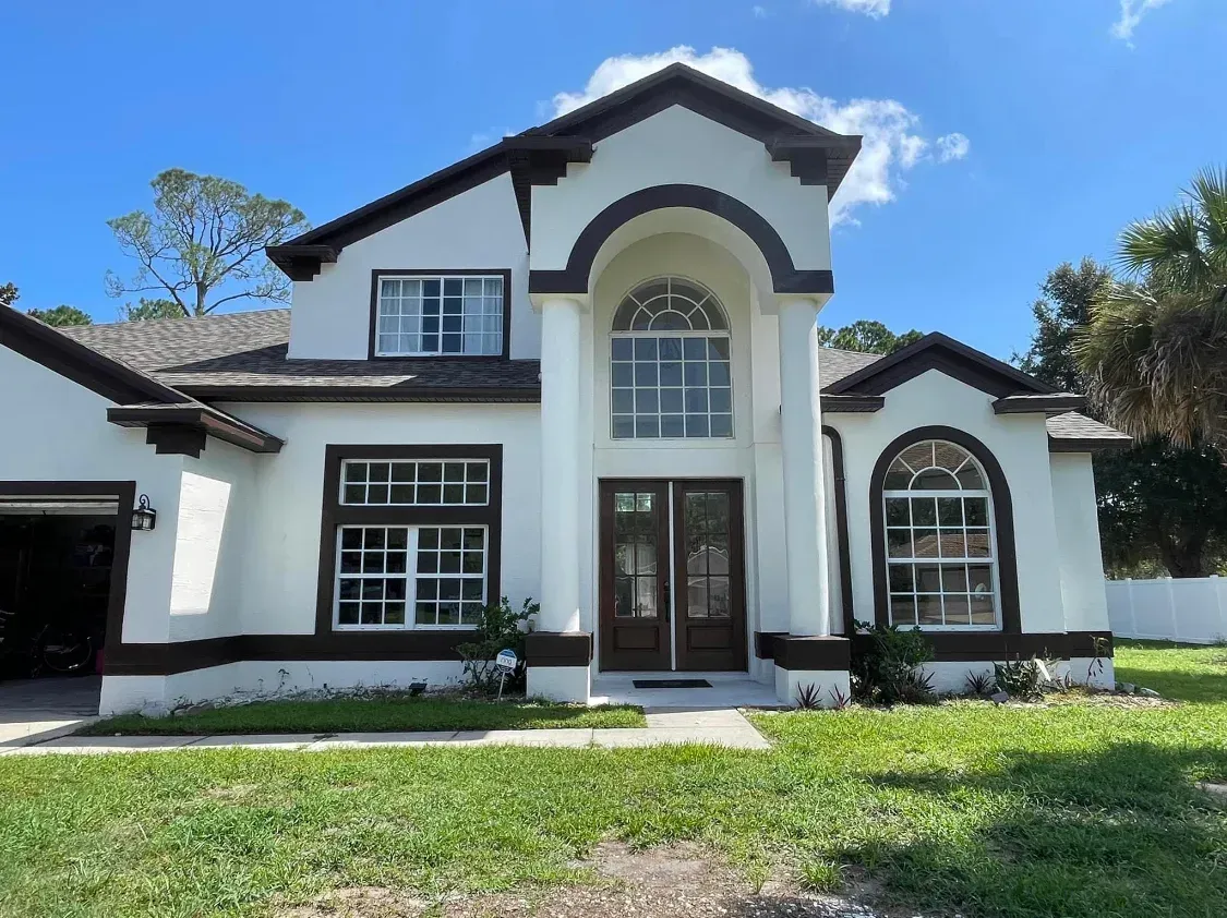 A white house with brown trim and a lot of windows