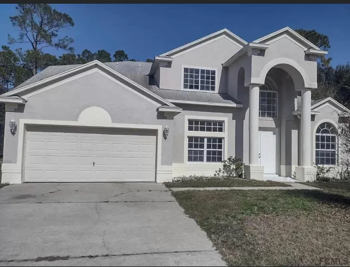 A large house with a white garage door is for sale