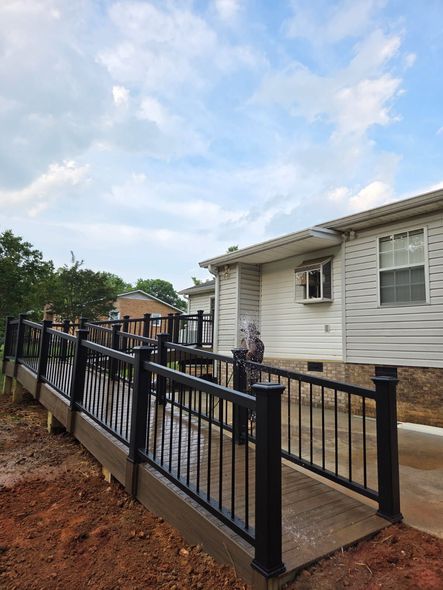 Ramp with black railings leading to a white building. Cloudy sky overhead.