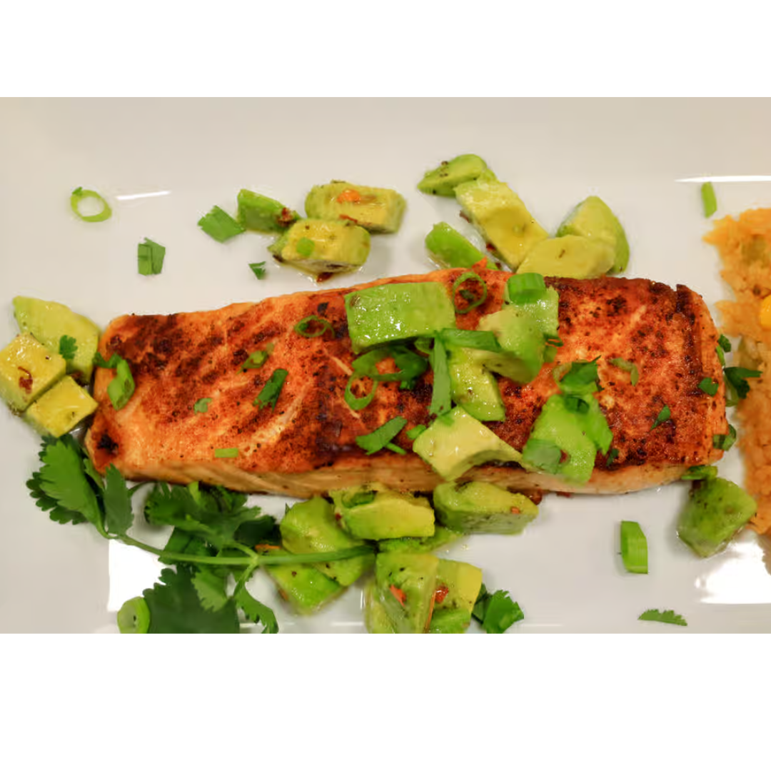 A white plate topped with a piece of salmon and avocado