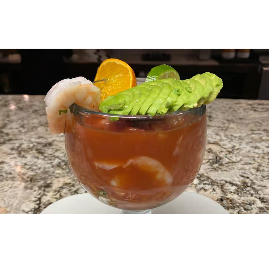 A bowl of shrimp , avocado , and orange slices on a table.