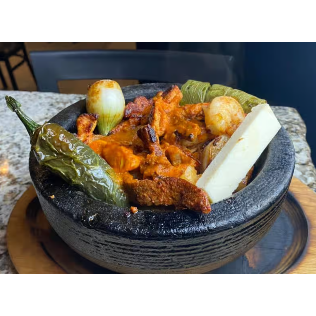 A bowl of food with vegetables and cheese on a table.