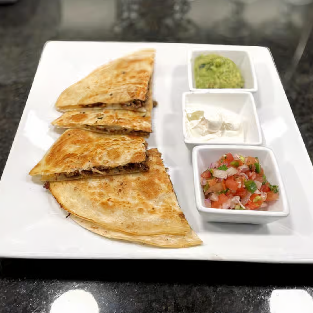 A white plate topped with quesadillas , guacamole , sour cream and salsa.