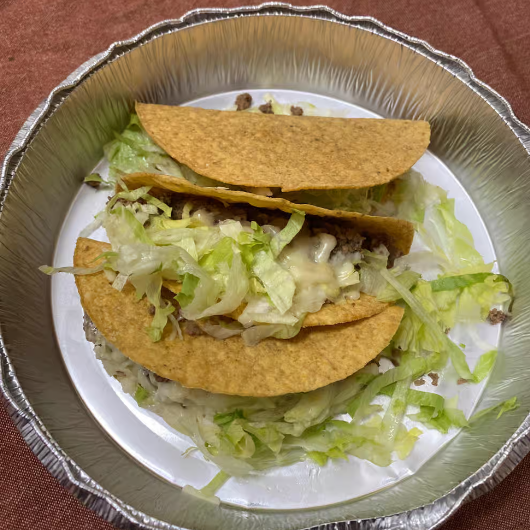 A plate of tacos with lettuce and cheese on a table.