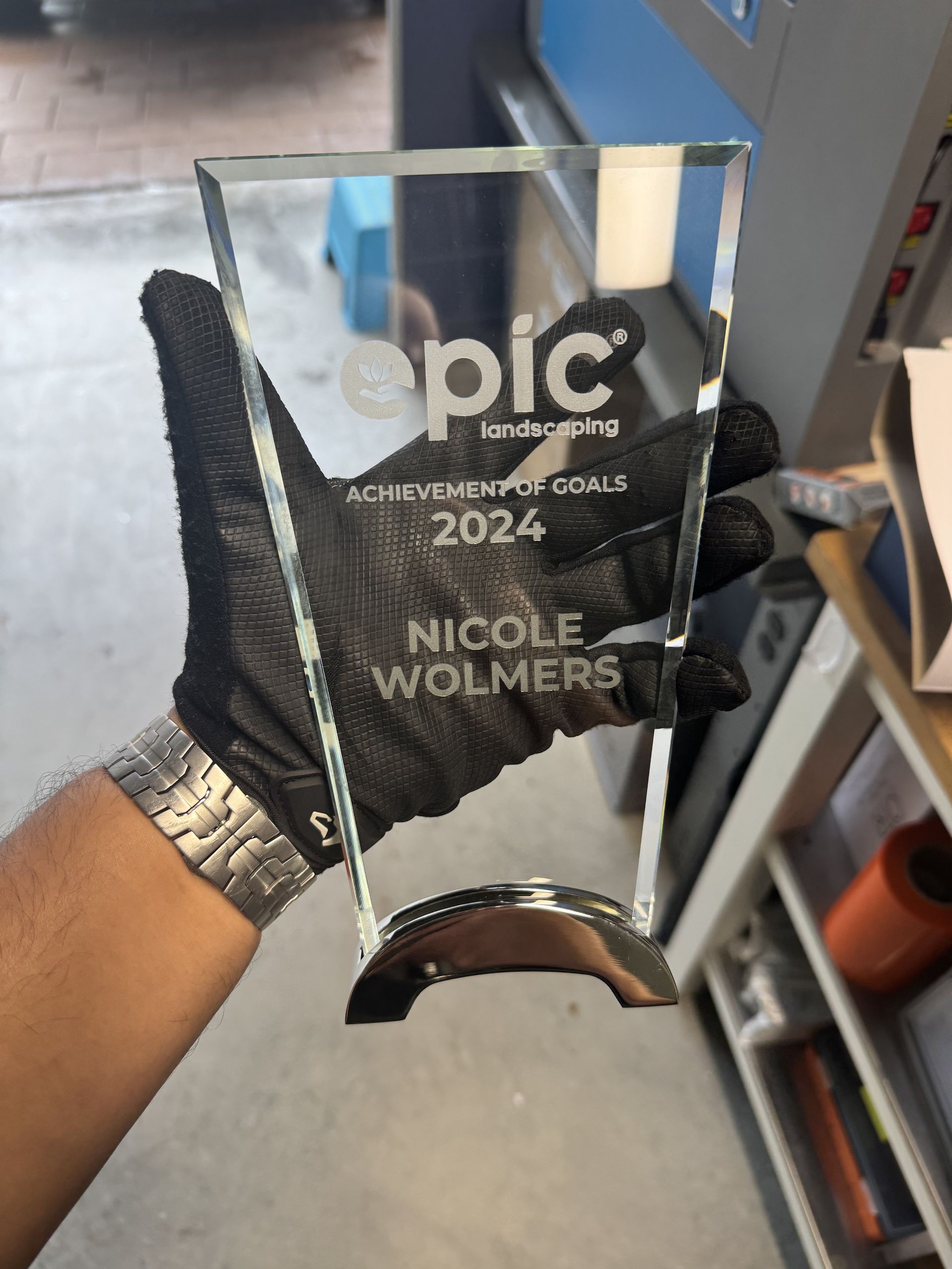 Gloved hand holding a clear glass award with 