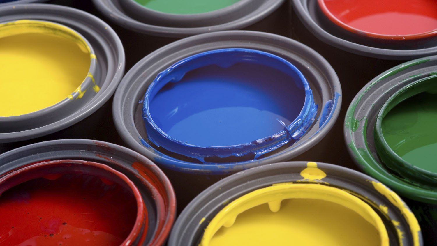 Open paint cans filled with red, yellow, blue, and green paint.