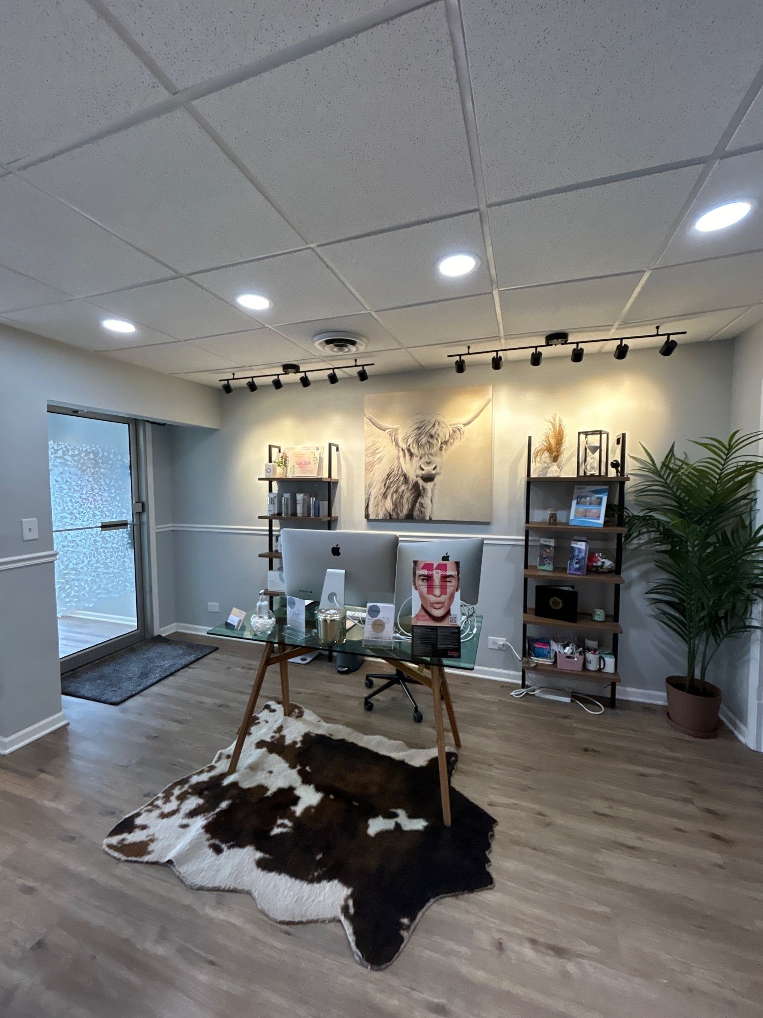 A living room with a cowhide rug on the floor and a desk.