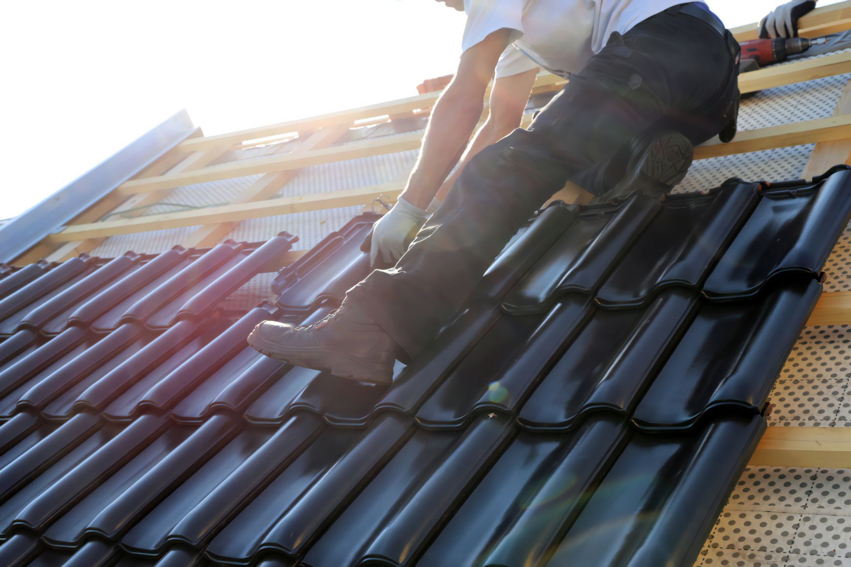 A Man is Working on the Roof of a Building — Stormguard Roofing In Caloundra West, QLD