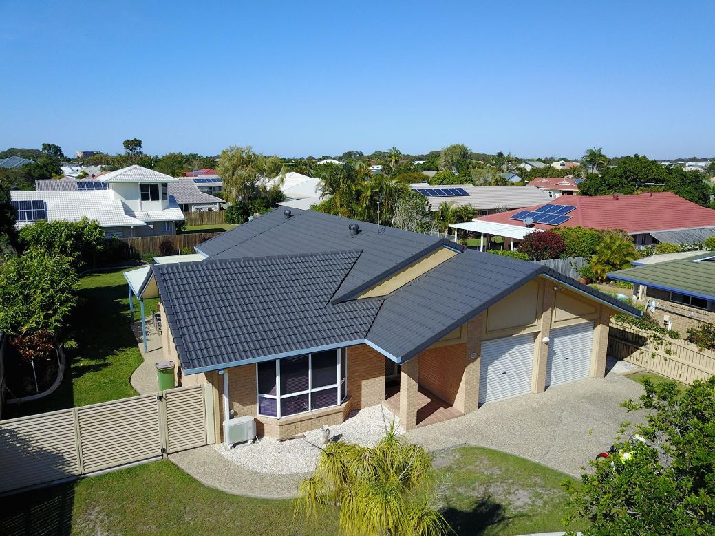 An Aerial View of a House With a Black Roof in a Residential Area — Stormguard Roofing In Caloundra West, QLD