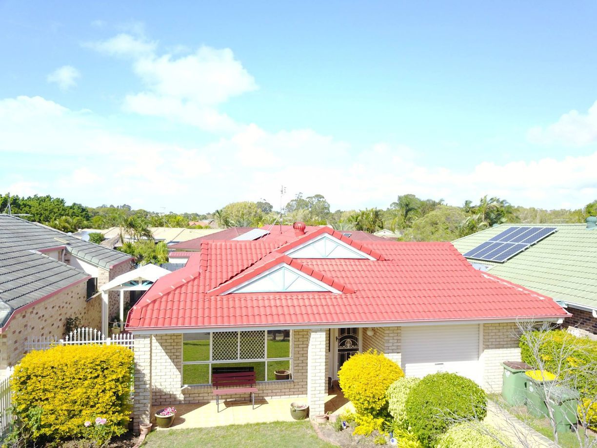 An Aerial View of a House With a Red Roof and Solar Panels — Stormguard Roofing In Caloundra West, QLD