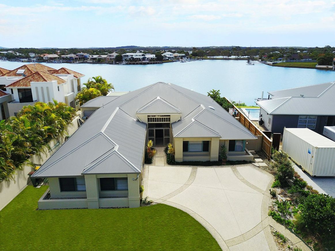An Aerial View of a House Next to a Body of Water — Stormguard Roofing In Caloundra West, QLD