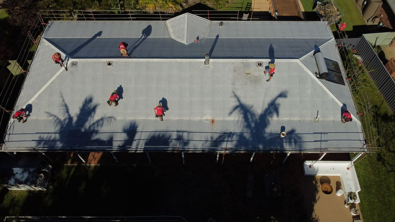 A Group of People Are Working on the Roof of a House — Stormguard Roofing In Caloundra West, QLD