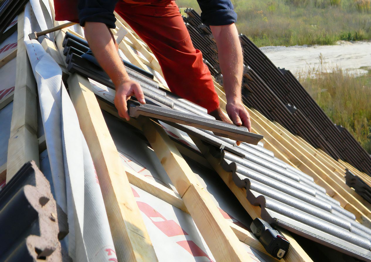 A Man is Working on the Roof of a House — Stormguard Roofing In Caloundra West, QLD
