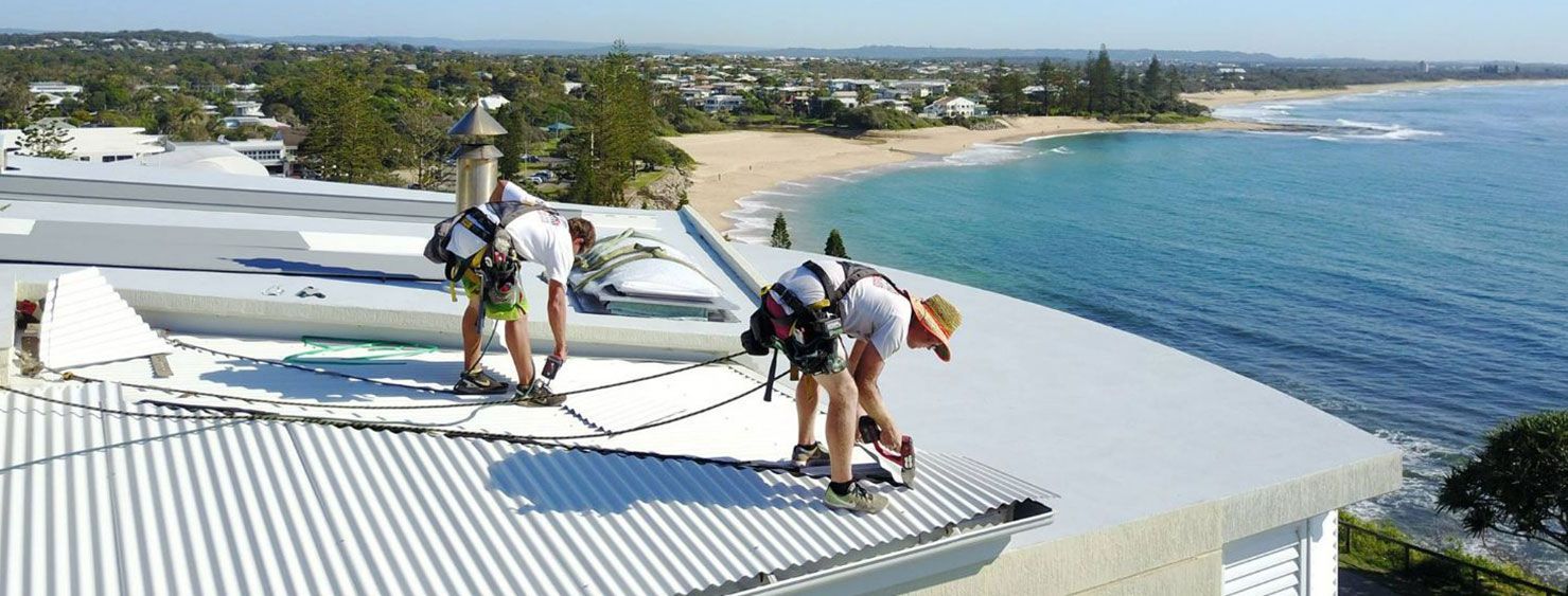 A Man Are Working on a Red Tiled Roof — Stormguard Roofing In Caloundra West, QLD