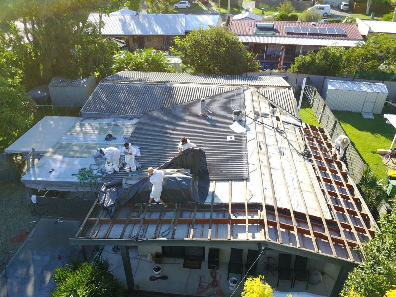 Aerial view of roof being repaired by workers in white suits. — Stormguard Roofing In Caloundra West, QLD