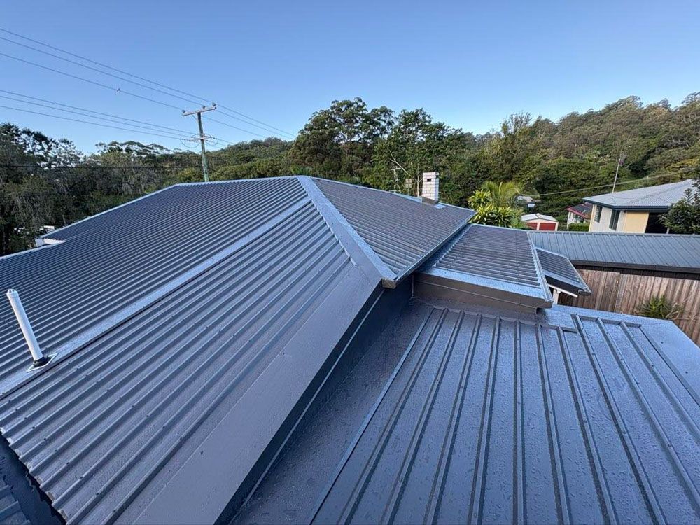 A Man is Installing Tiles on the Roof of a House — Stormguard Roofing In Caloundra West, QLD