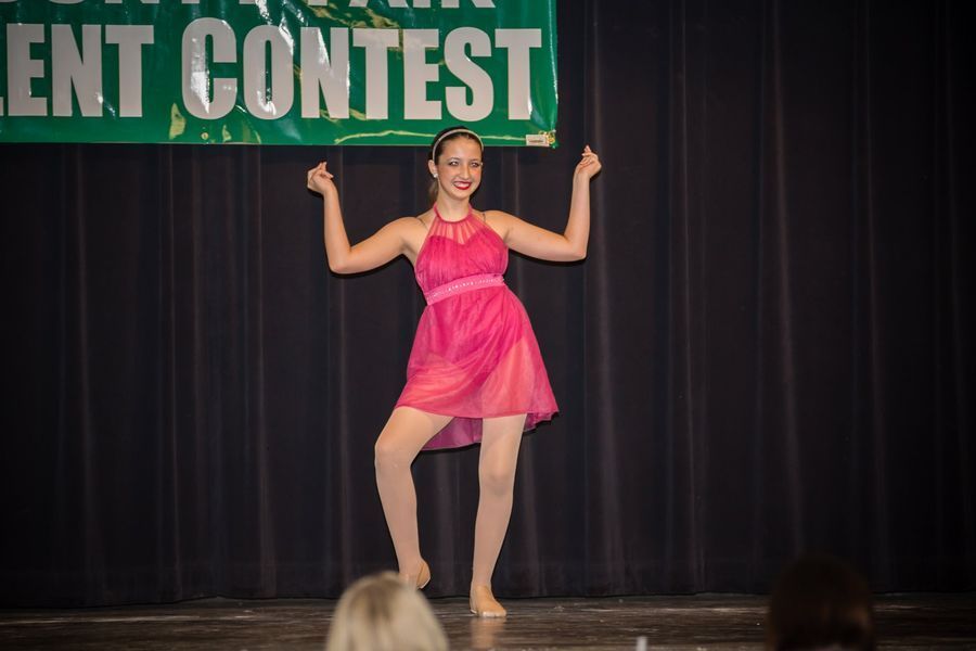 Woman in a pink dress posing on stage during a talent contest