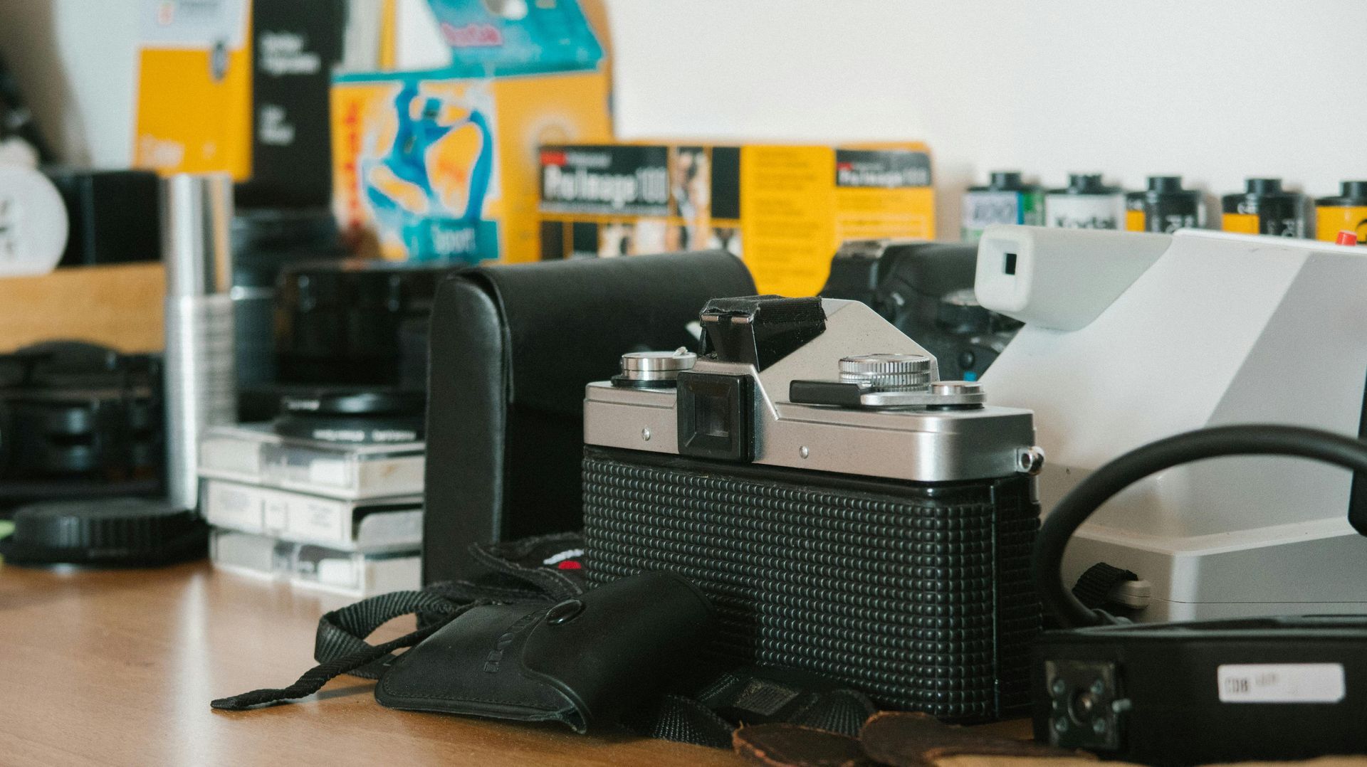 Vintage camera and film canister on a desk with other photography gear in the background
