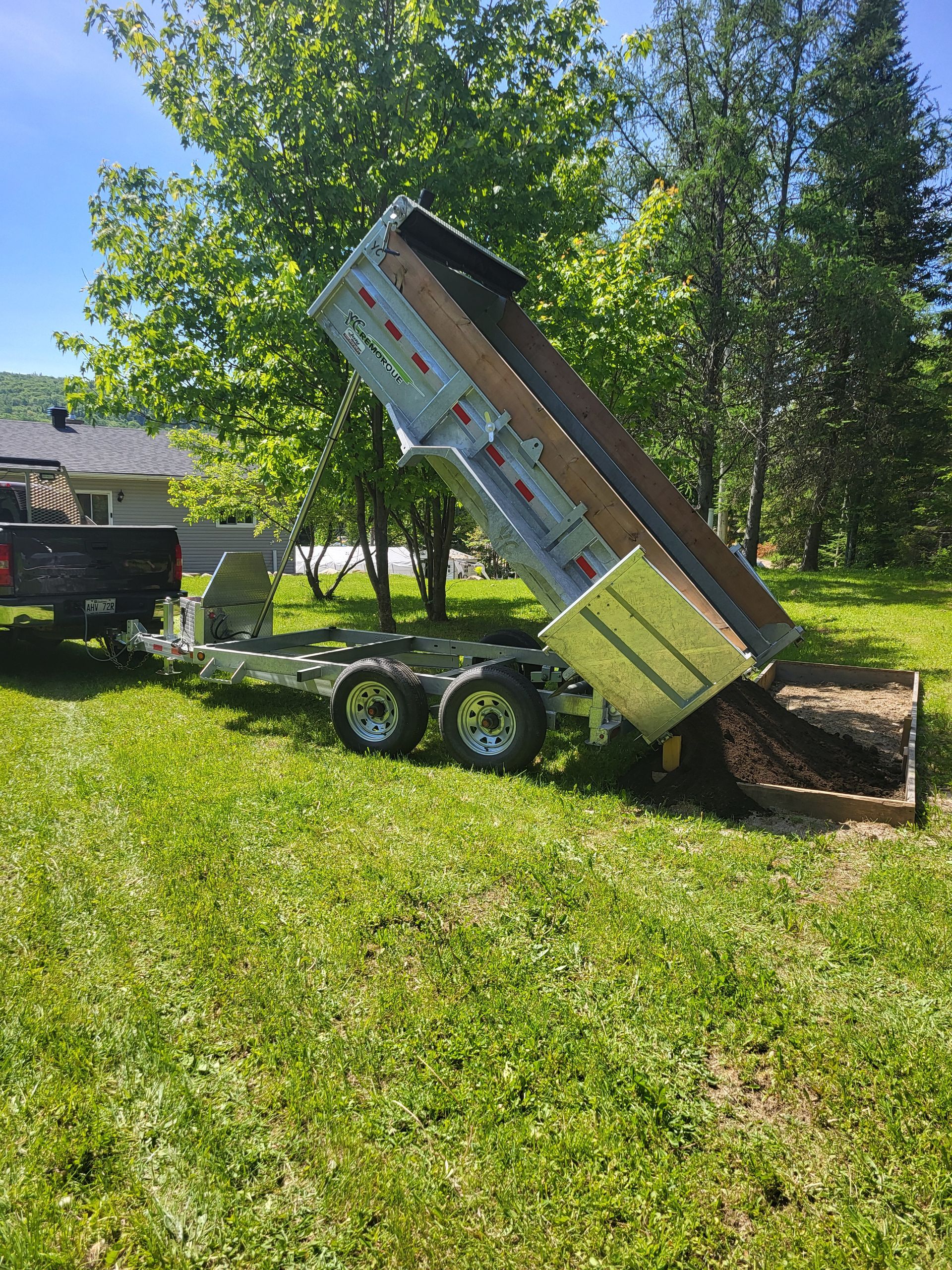 Une remorque à benne basculante est posée sur un champ vert luxuriant.