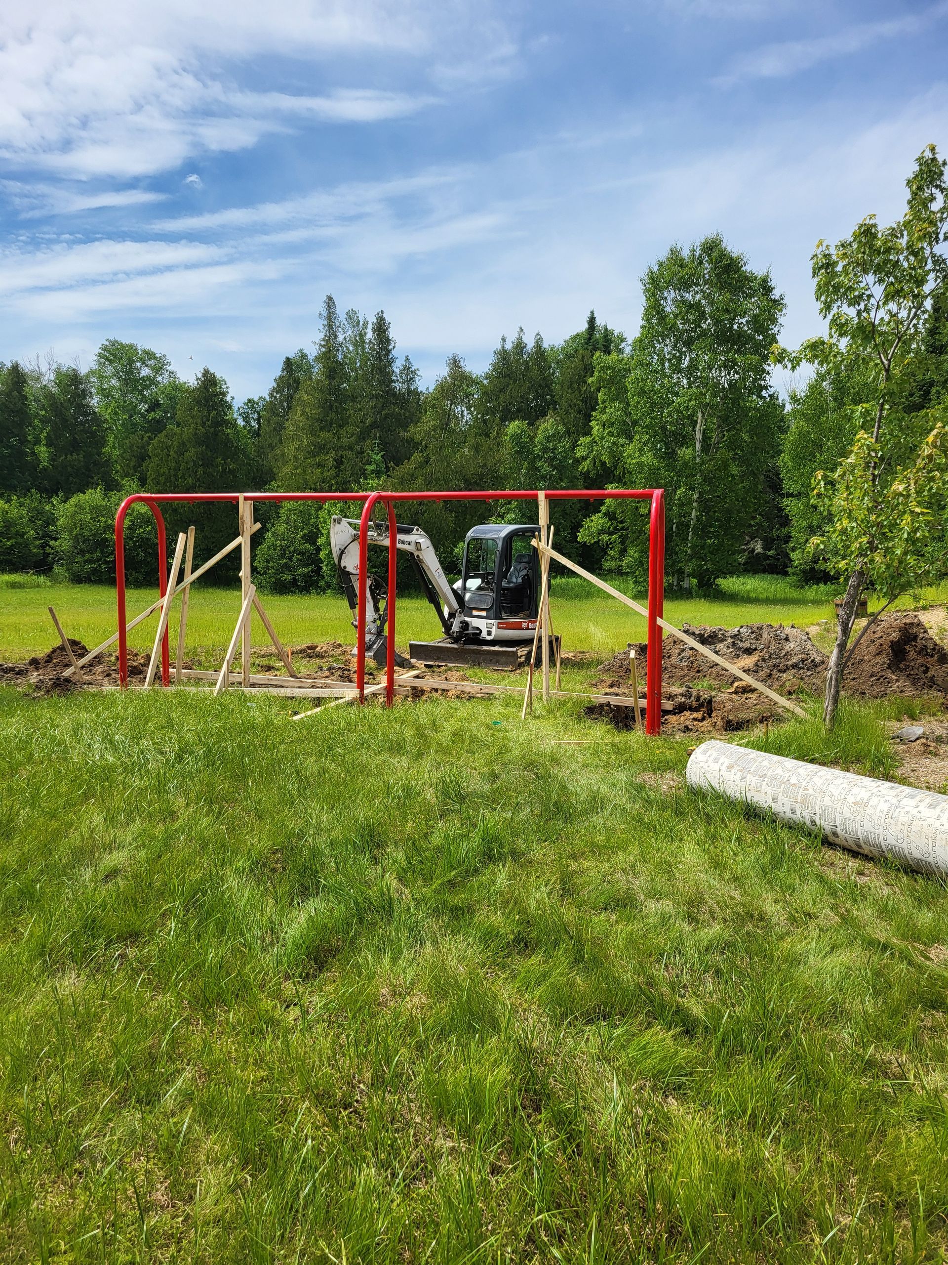 Une balançoire rouge est en cours de construction dans un champ herbeux.