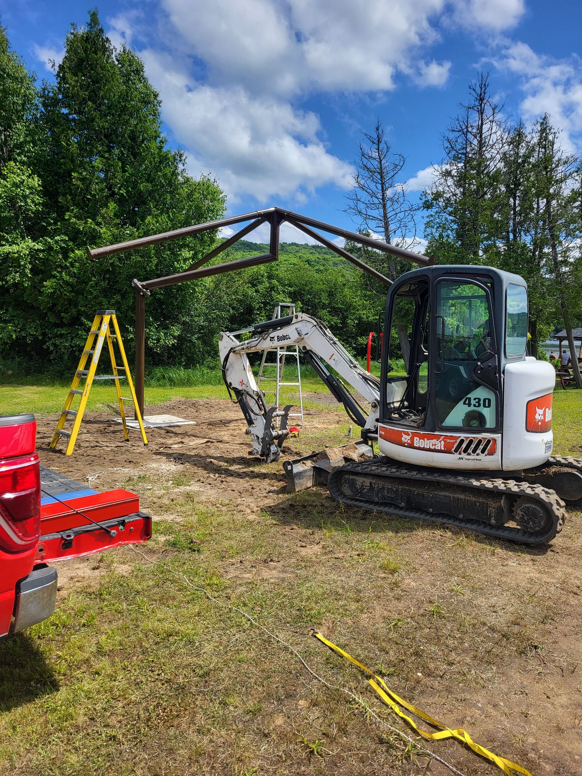Une petite excavatrice est assise dans un champ à côté d'une échelle.