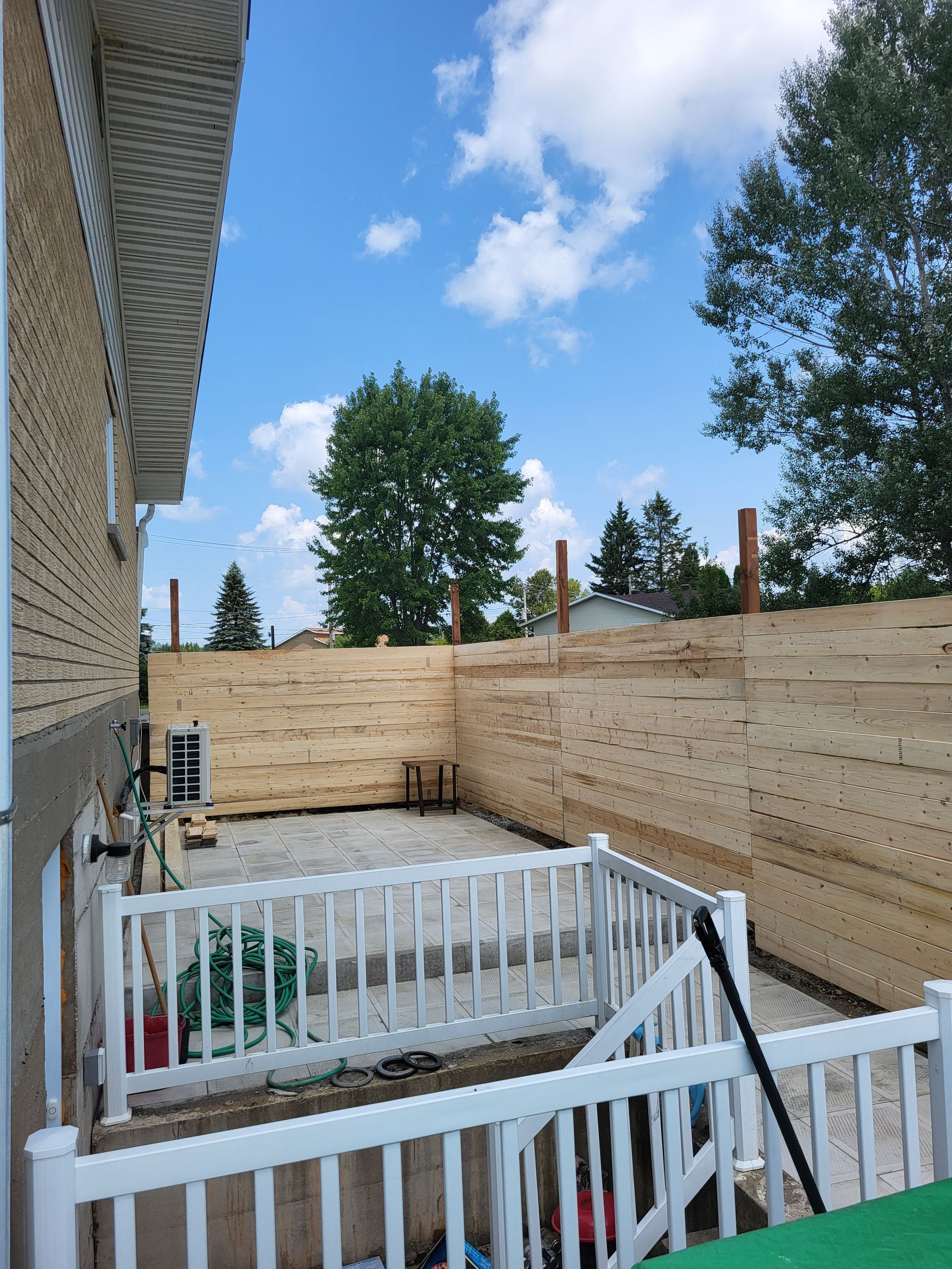 Une cour arrière avec une clôture en bois et une balustrade blanche.