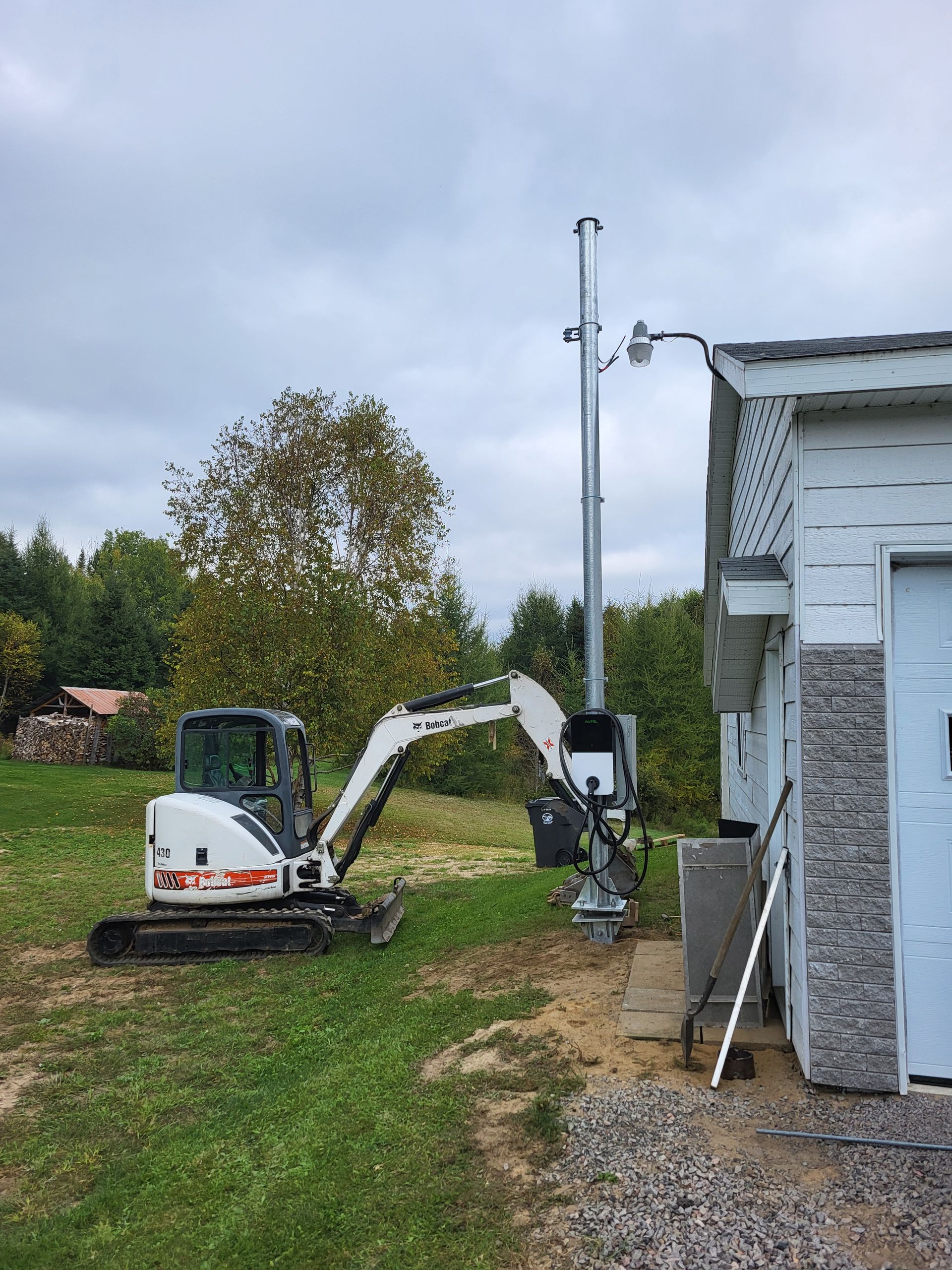 Une petite excavatrice est garée devant une maison.