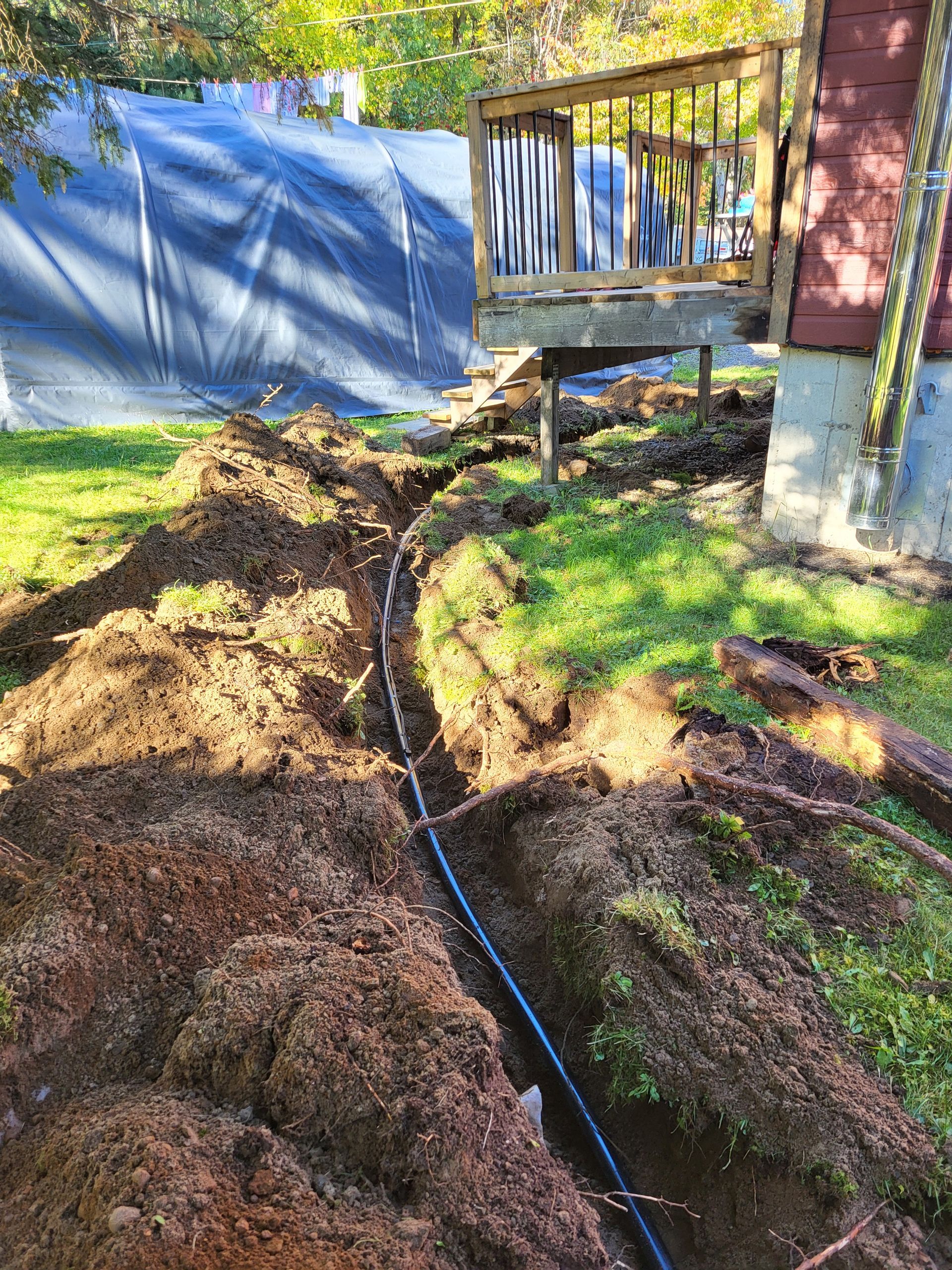 Un tuyau est en train d'être installé dans la terre devant une maison.
