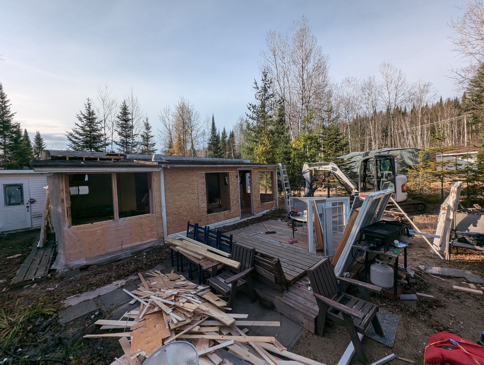Une maison est en train d'être démolie avec un bulldozer en arrière-plan.