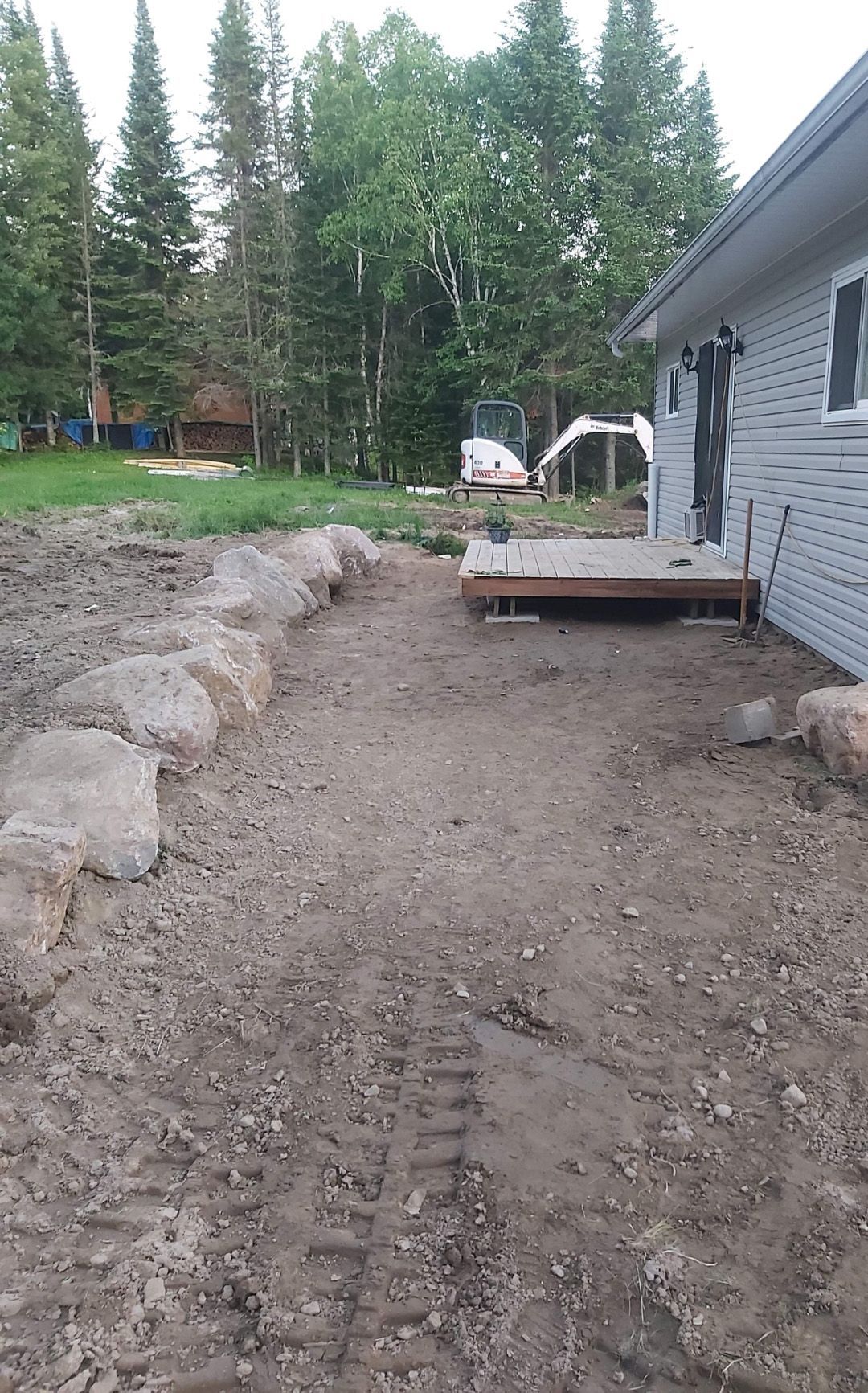 Un chemin de terre menant à une maison avec des arbres en arrière-plan.