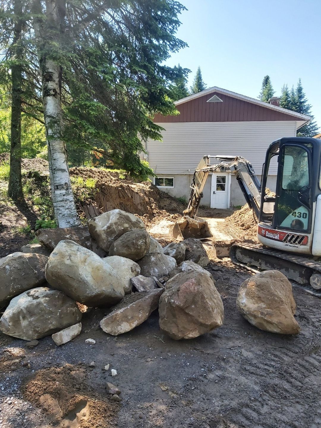 Un tas de pierres et un bulldozer devant une maison.