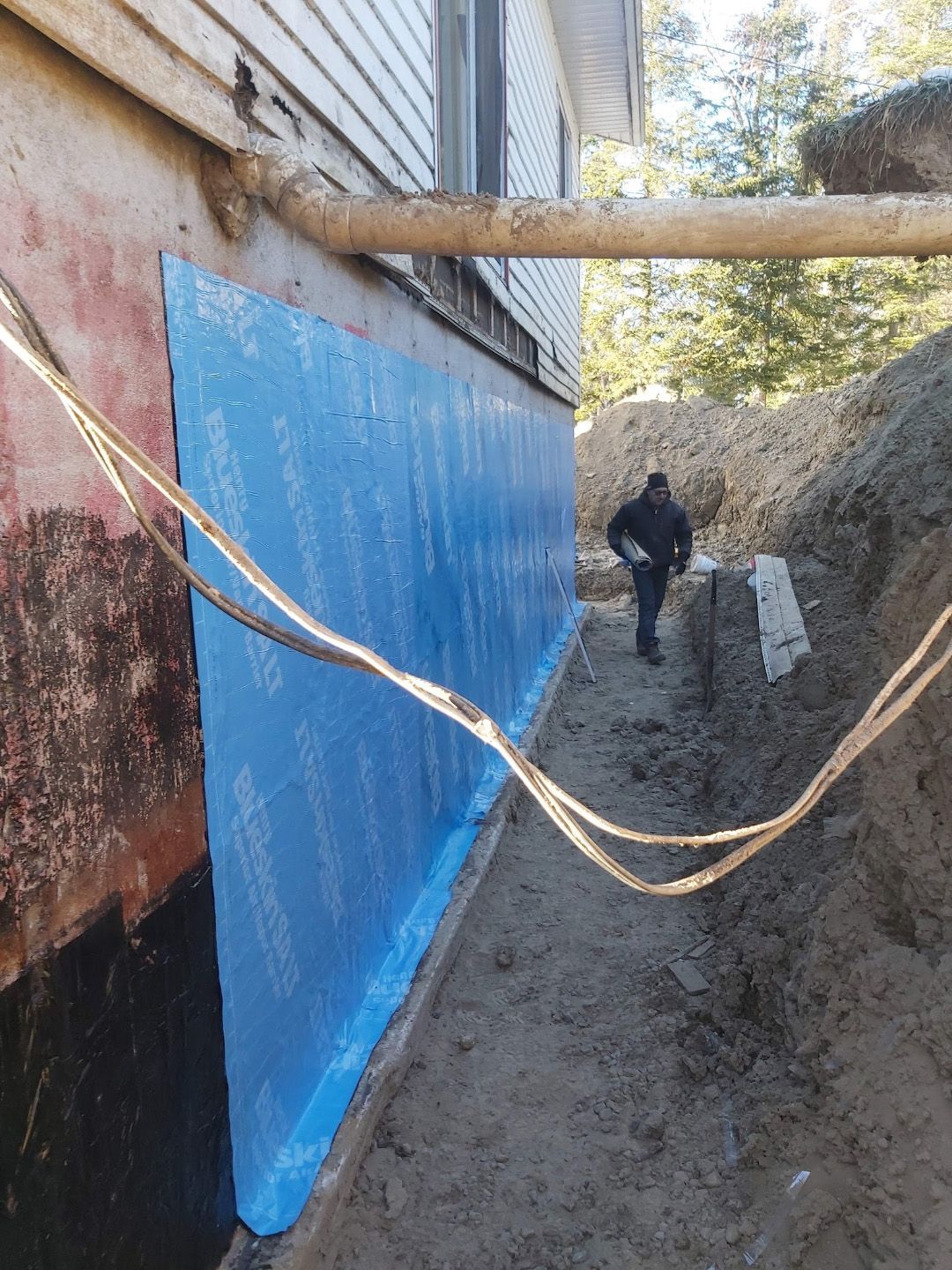 Un homme marche sur un chemin de terre à côté d'une maison.