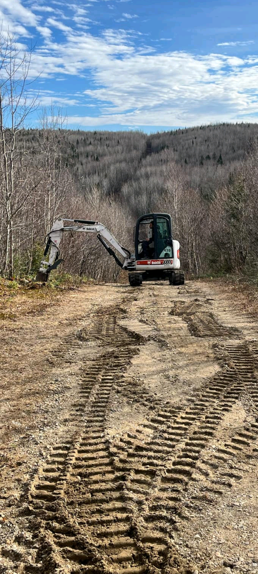 Un bulldozer roule sur un chemin de terre dans les bois.