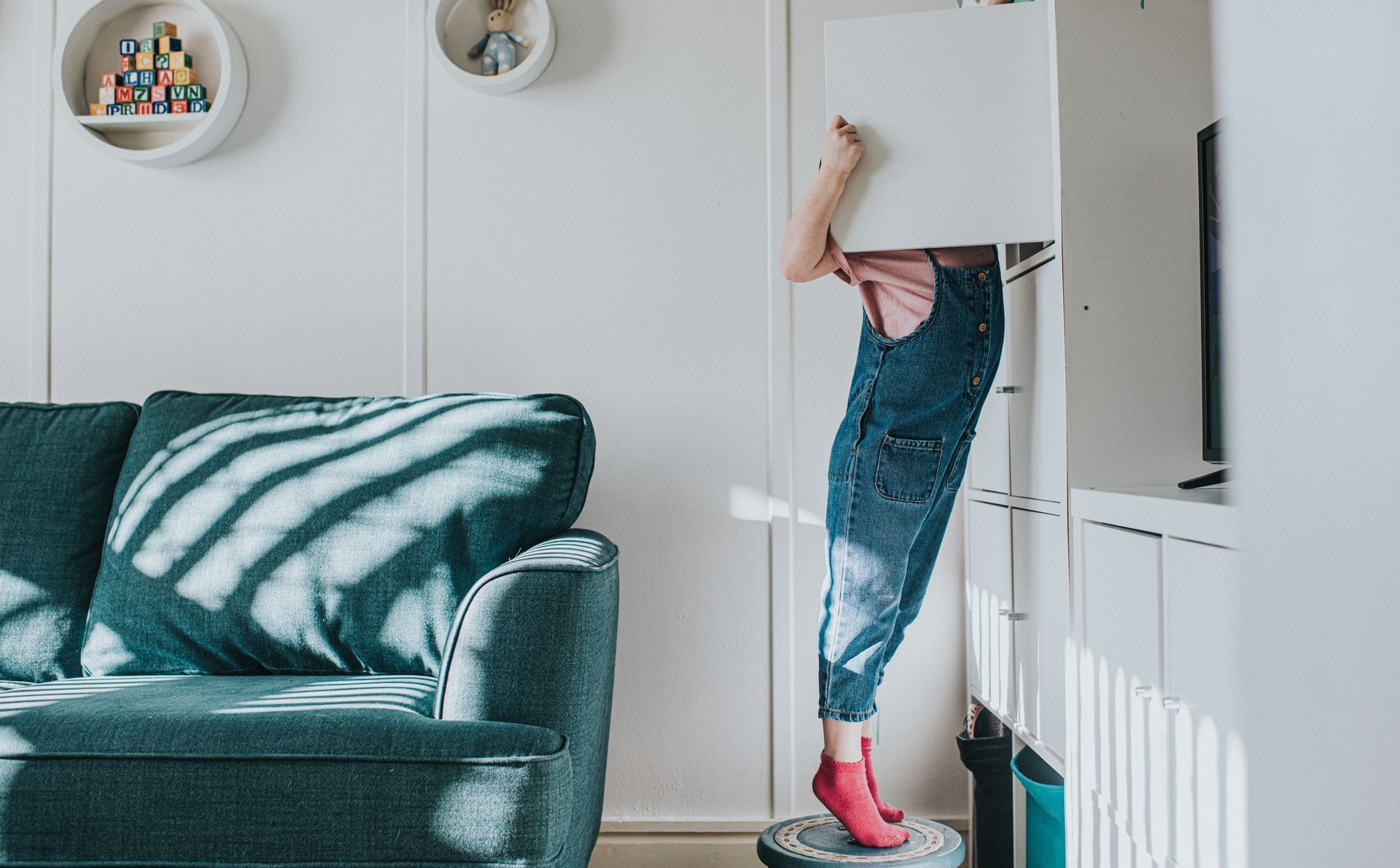 A child is standing on a vacuum cleaner in a living room.