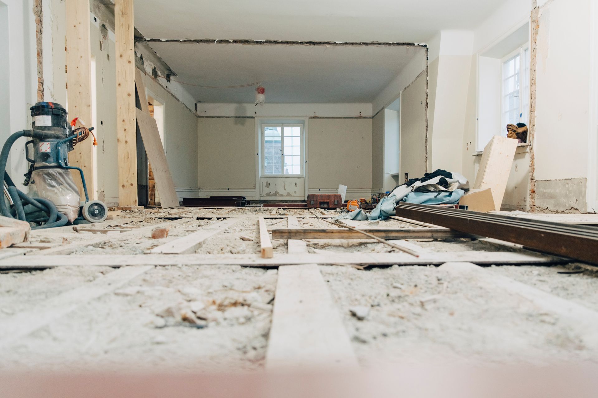 A room under construction with a vacuum cleaner on the floor.