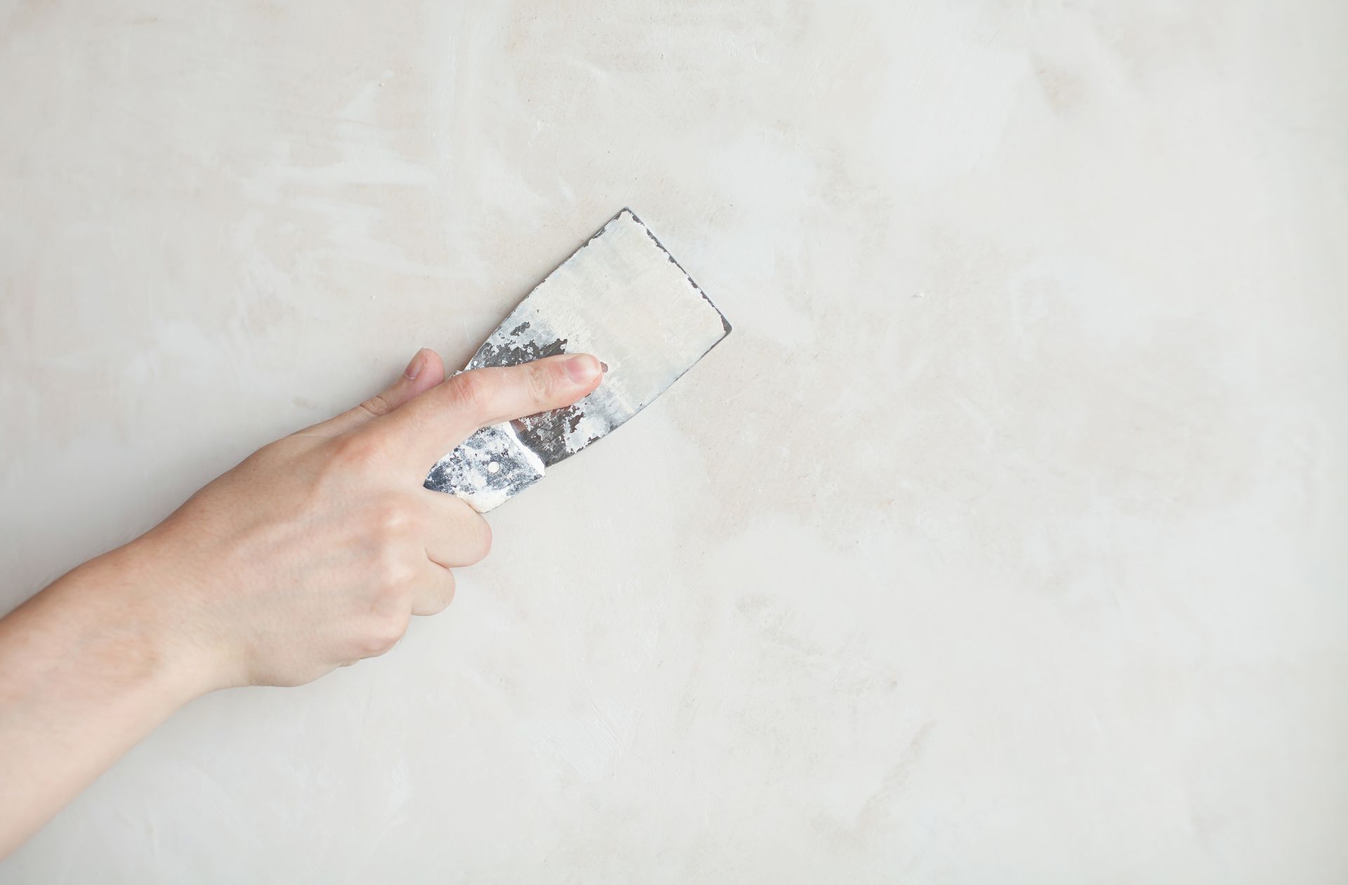 A person is plastering a wall with a spatula.