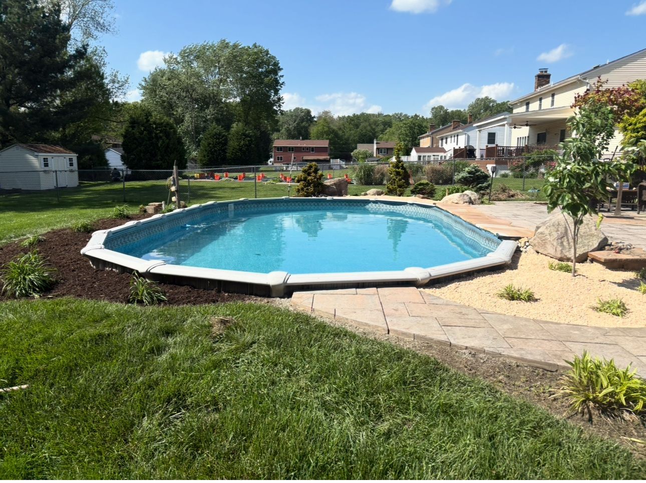 A large swimming pool is sitting in the middle of a lush green yard.