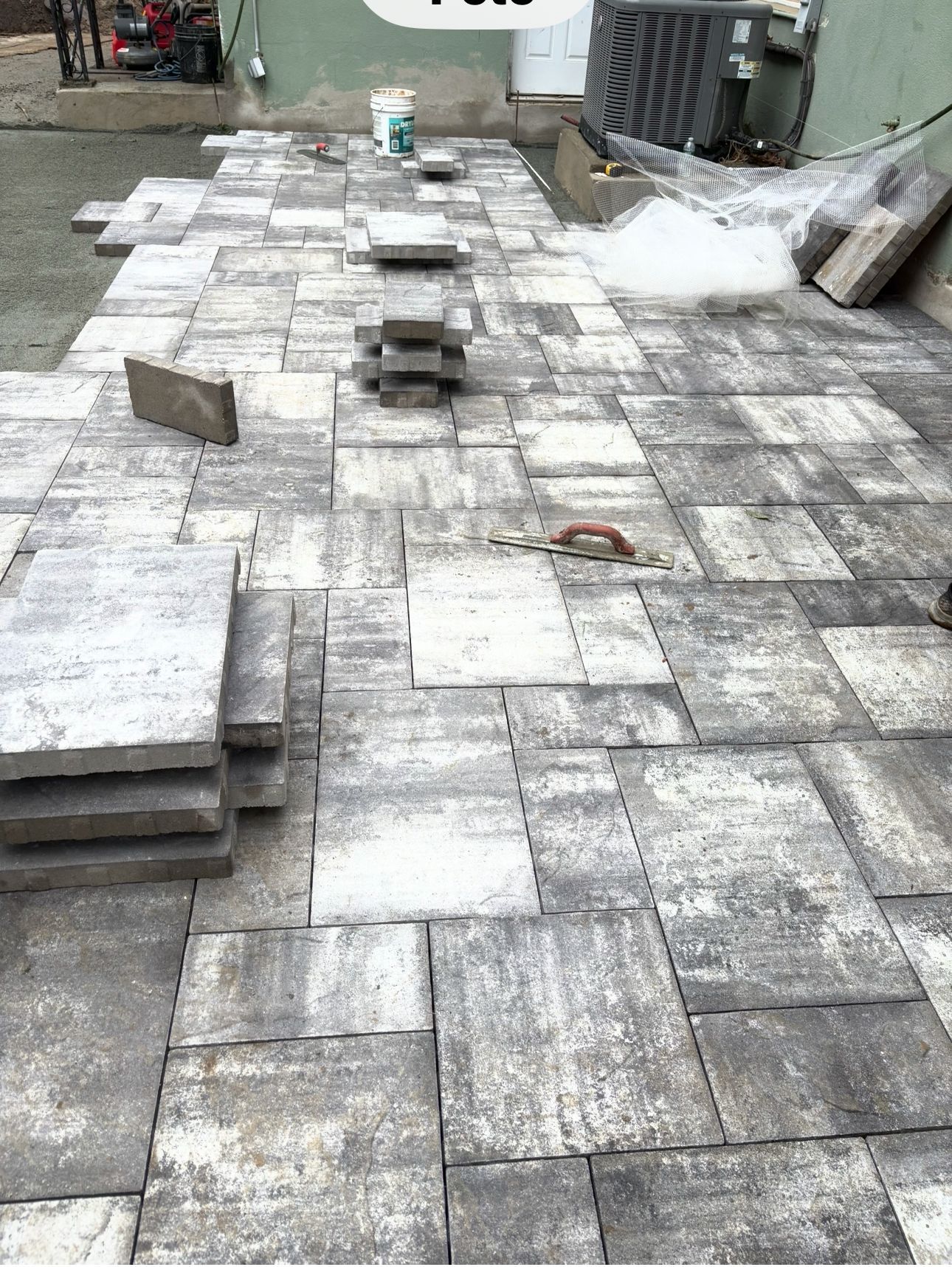 A brick walkway is being built in a backyard.