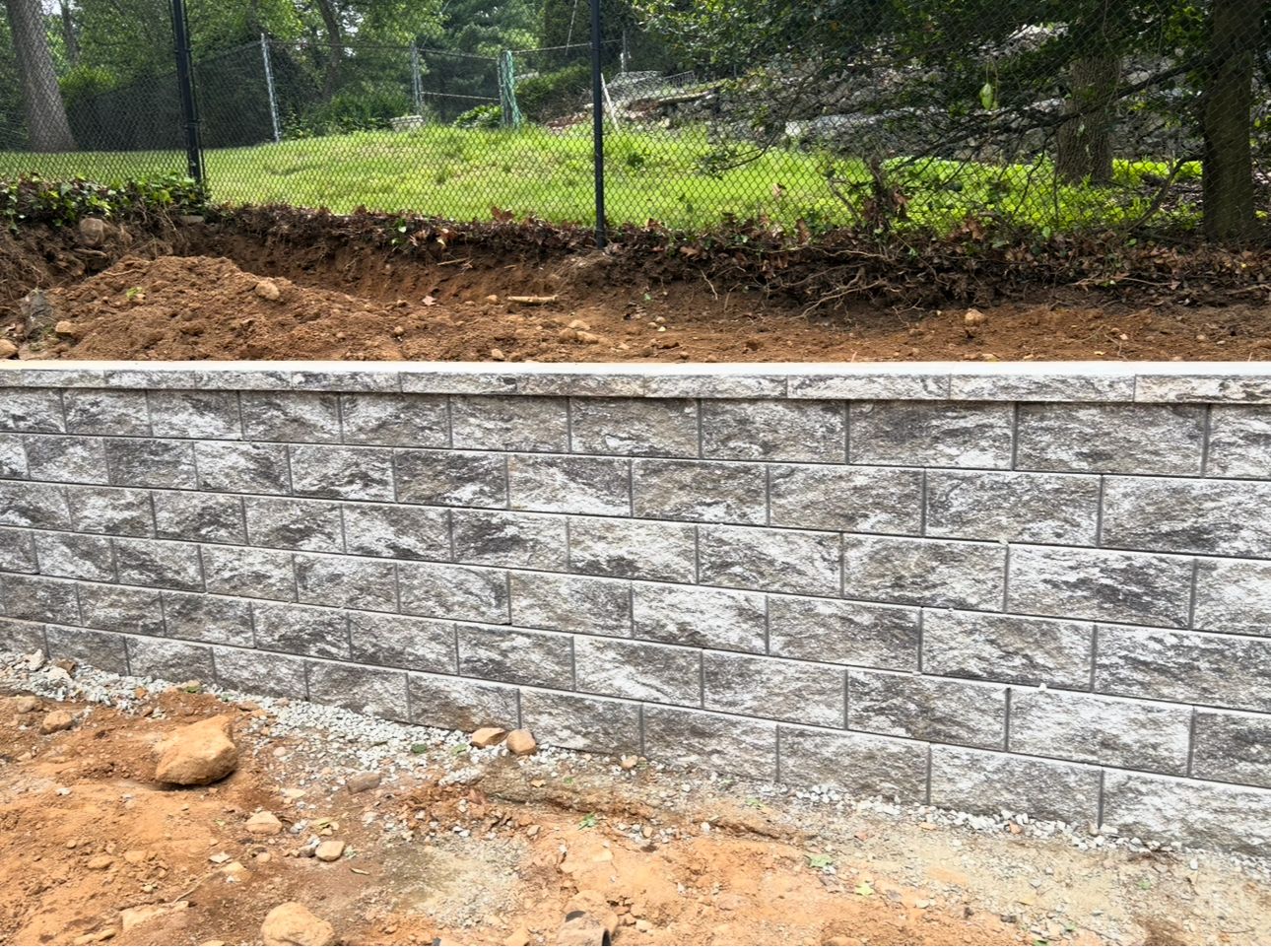 A brick wall is being built in the middle of a dirt field.