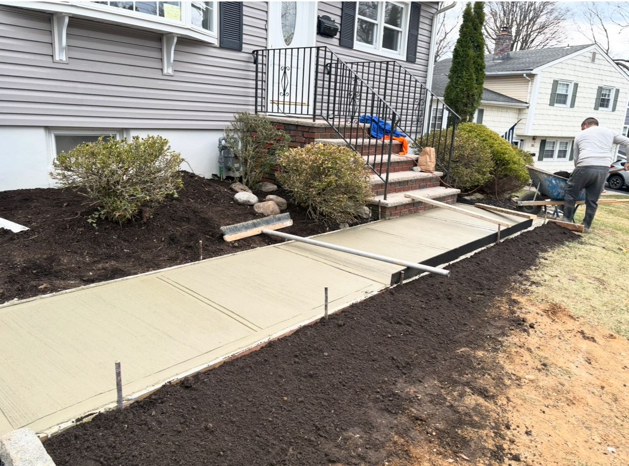 A concrete walkway is being built in front of a house.