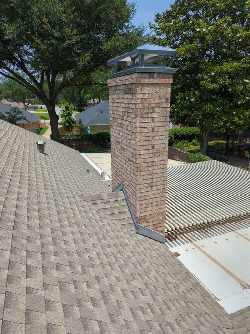 A brick chimney is on the roof of a house.