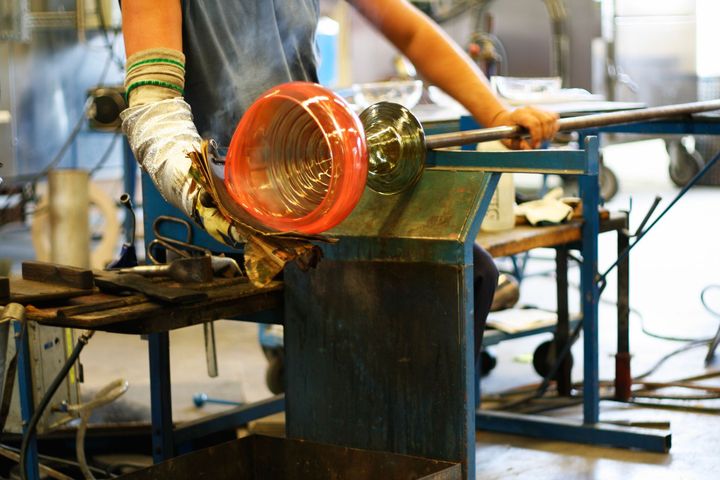 A person is sitting at a table making a glass object.