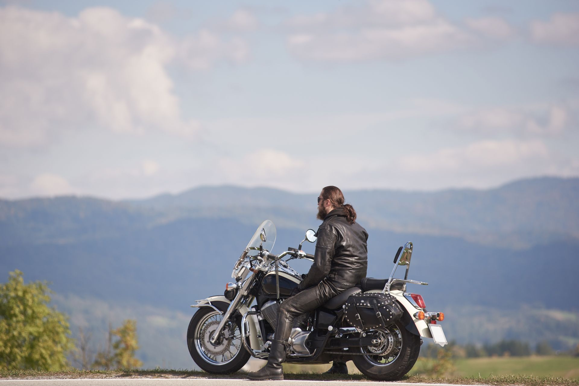 Man on motorcycle, overlooking a mountainous landscape, enjoying the view.