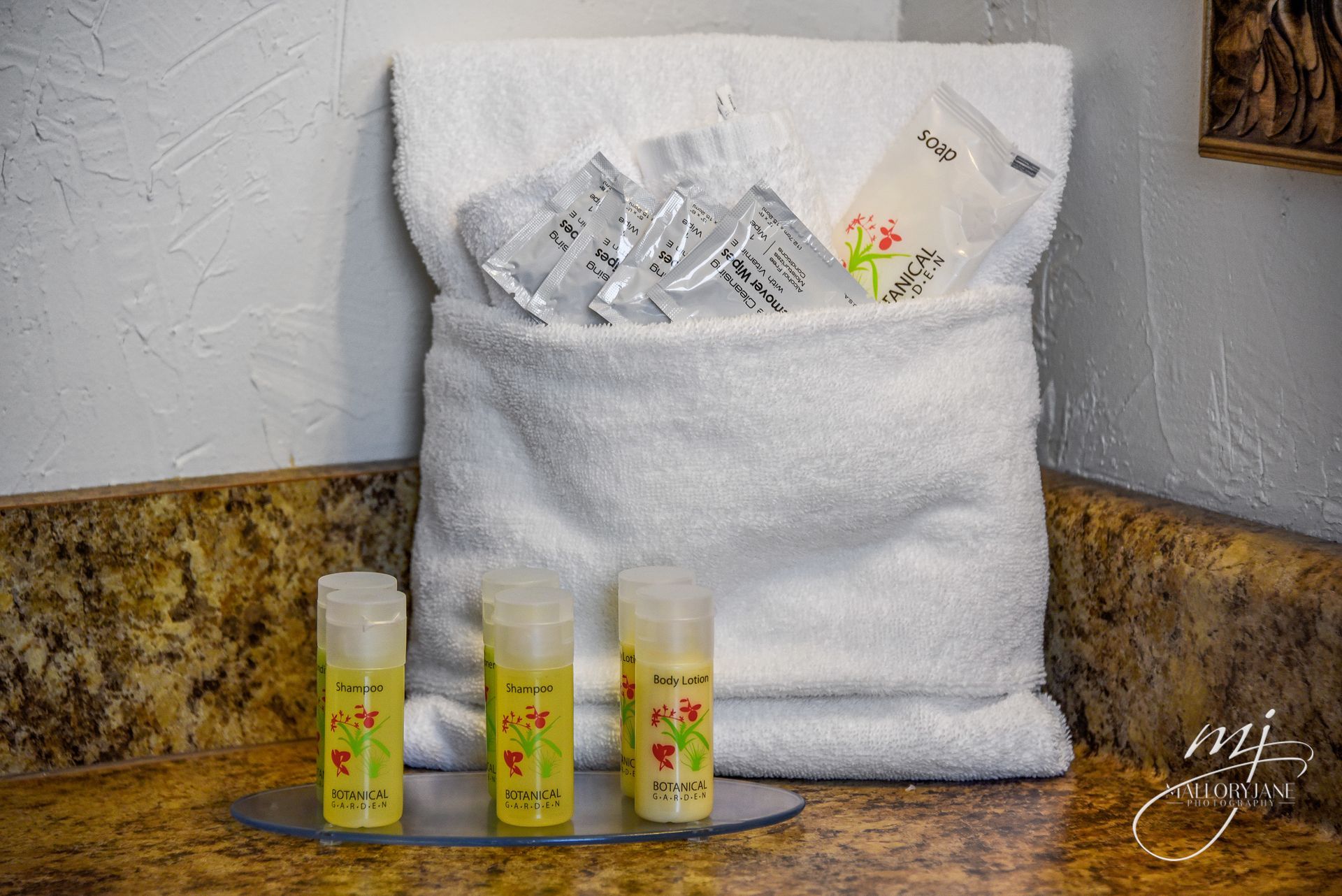 White towel with toiletries, including shampoo and packets, on a countertop.