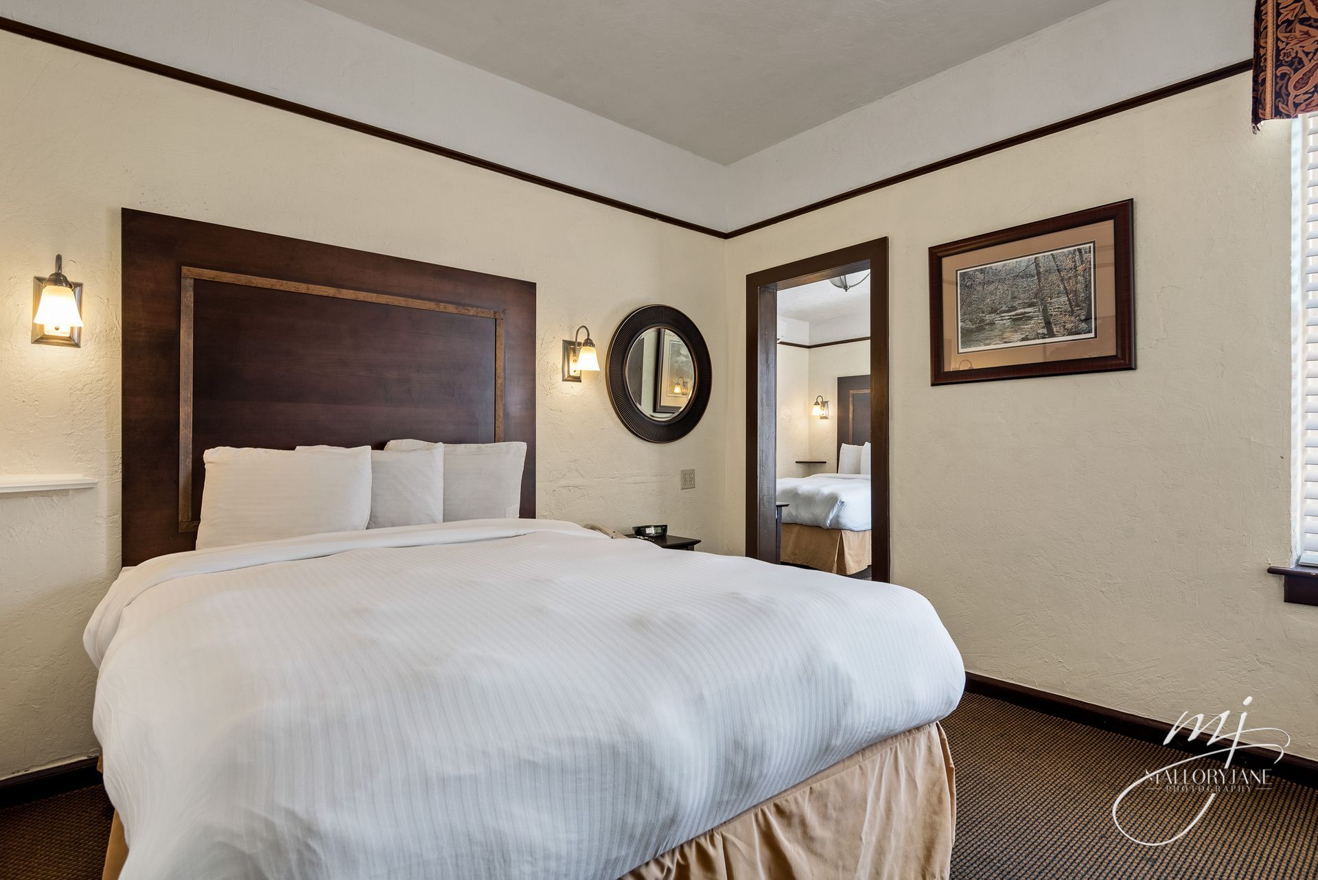 Bedroom with a large bed, dark wood headboard, and a doorway to another room.