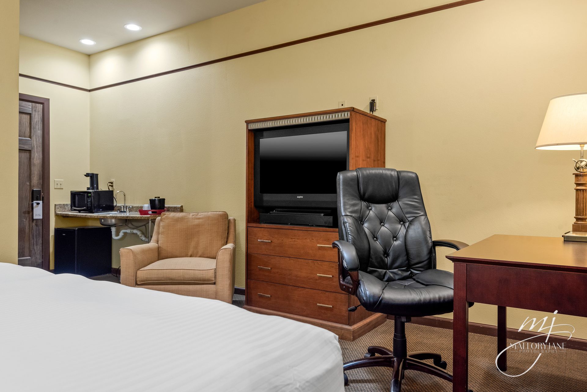 Hotel room with bed, chair, desk, TV, and coffee station.