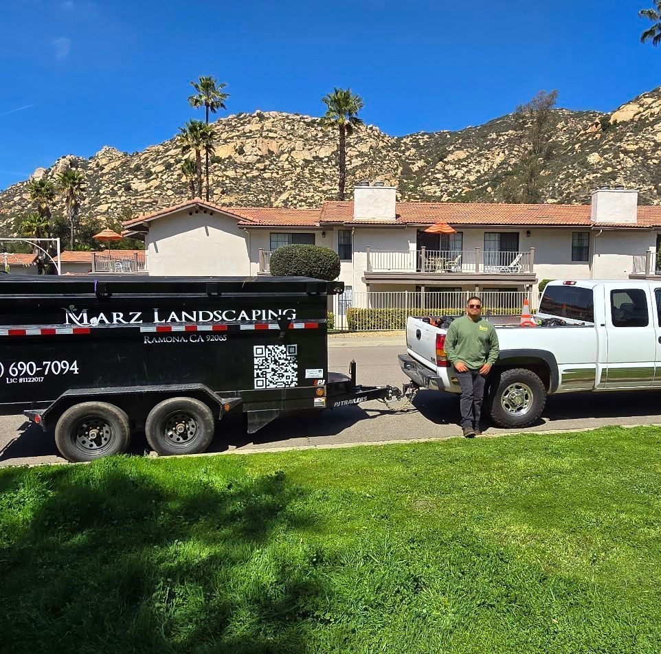Man standing by a white pickup truck towing a black trailer with 