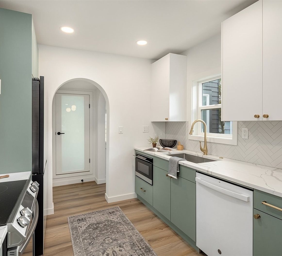 A kitchen with green cabinets , white counter tops , a stove and a dishwasher.