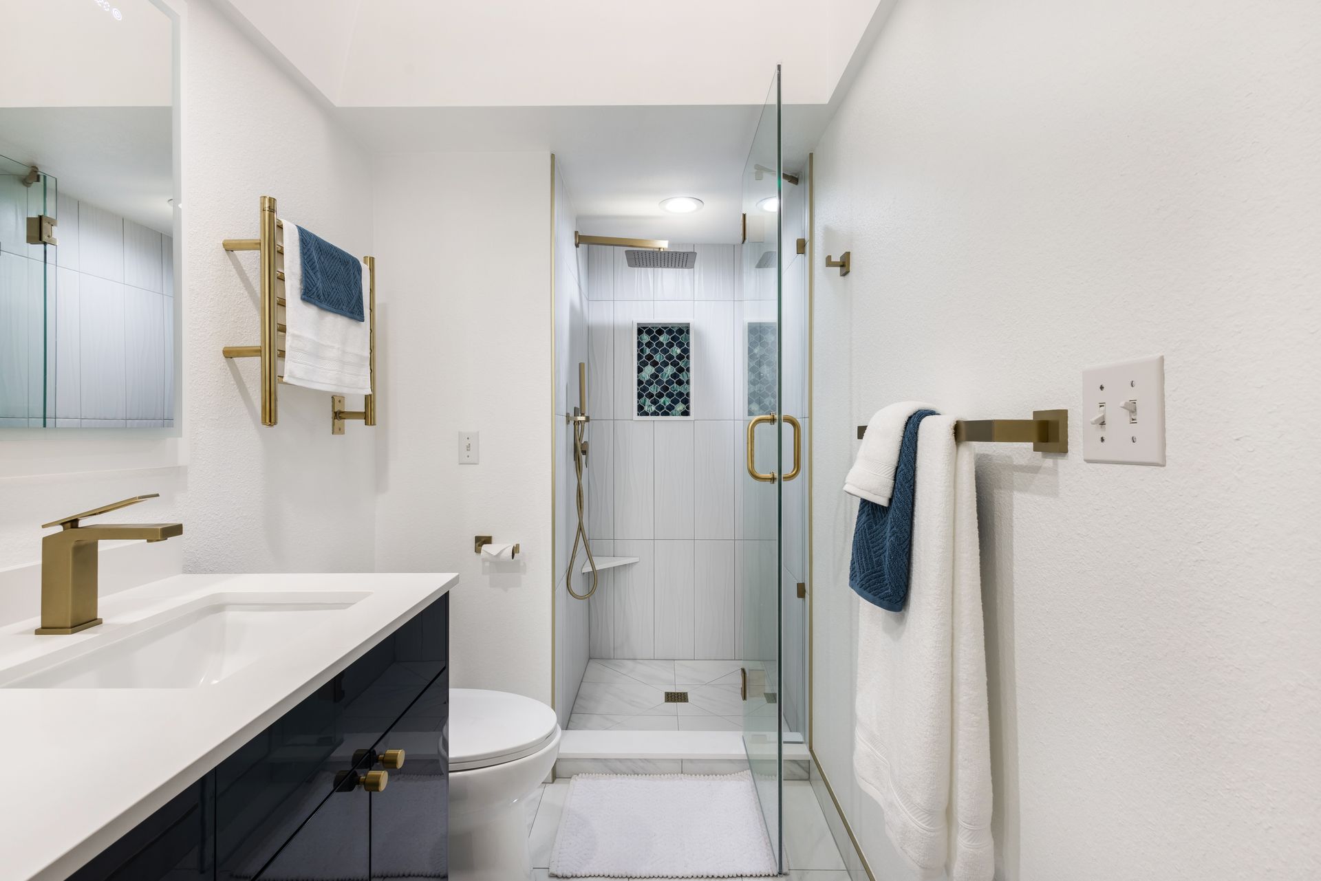 A bathroom with a toilet , sink , mirror and walk in shower.