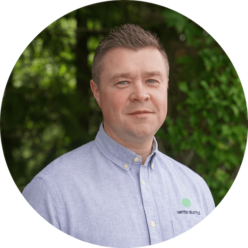 A man in a blue shirt is standing in a circle with trees in the background.